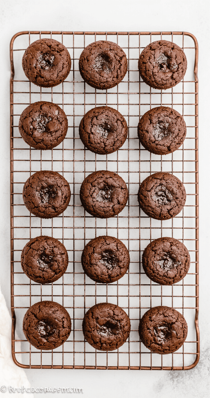 Keto Brownie Bites: Chocolade Geluk Zonder Schuldgevoel Cinematografisch overhead shot van zestien perfect gebakken keto brownie bites op een vintage koperen afkoelrek, met stoom die opstijgt en enkele doormidden gebroken brownie bites die de vochtige kruimstructuur tonen, op een rustiek houten aanrechtblad met cacaopoeder en amandelmeel.