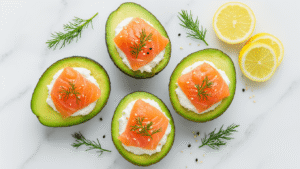 Avocado Gevuld met Zalm en Roomkaas: Het Ultieme Koolhydraatarme Recept Overhead shot van vier gevulde avocadohelften met zalm-roomkaas, garnished met dille en sesam op een marmeren ondergrond, omgeven door citroenpartjes en kruiden.