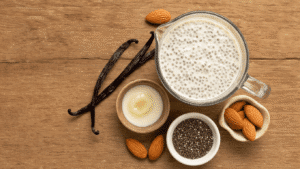 Vanille Chia Pudding met Amandelmelk: Het Makkelijkste Recept dat Je Nooit Meer Wilt Missen Een rustiek tafereel met amandelmelk, chiazaadjes, vanille-extract, een opengesneden vanillepeul, ahornsiroop en chia pudding in warm ochtendlicht, met een Scandinavische esthetiek en sfeervolle bokeh-achtergrond.